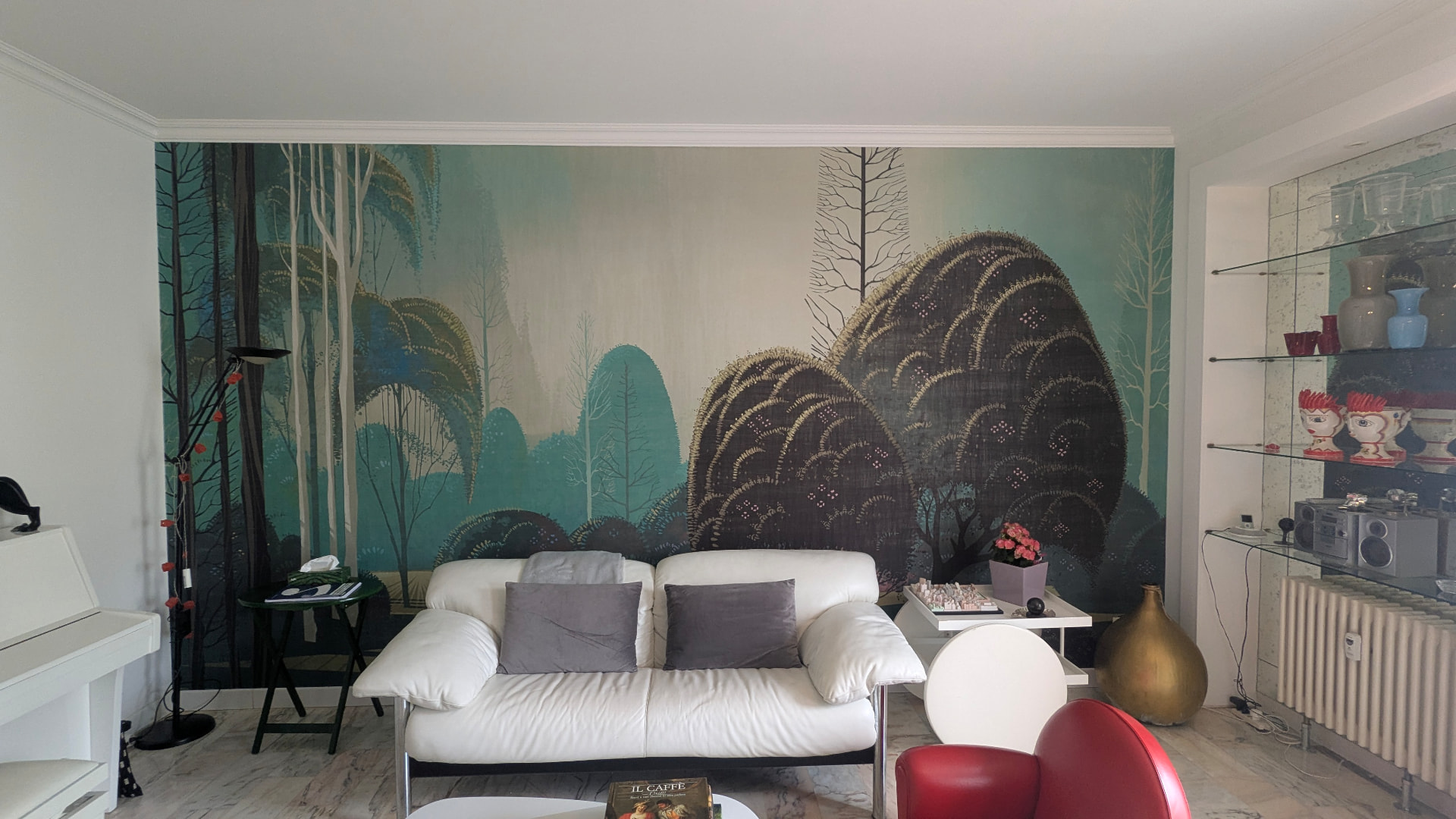 Murale con alberi stilizzati verde e oro dietro un divano bianco